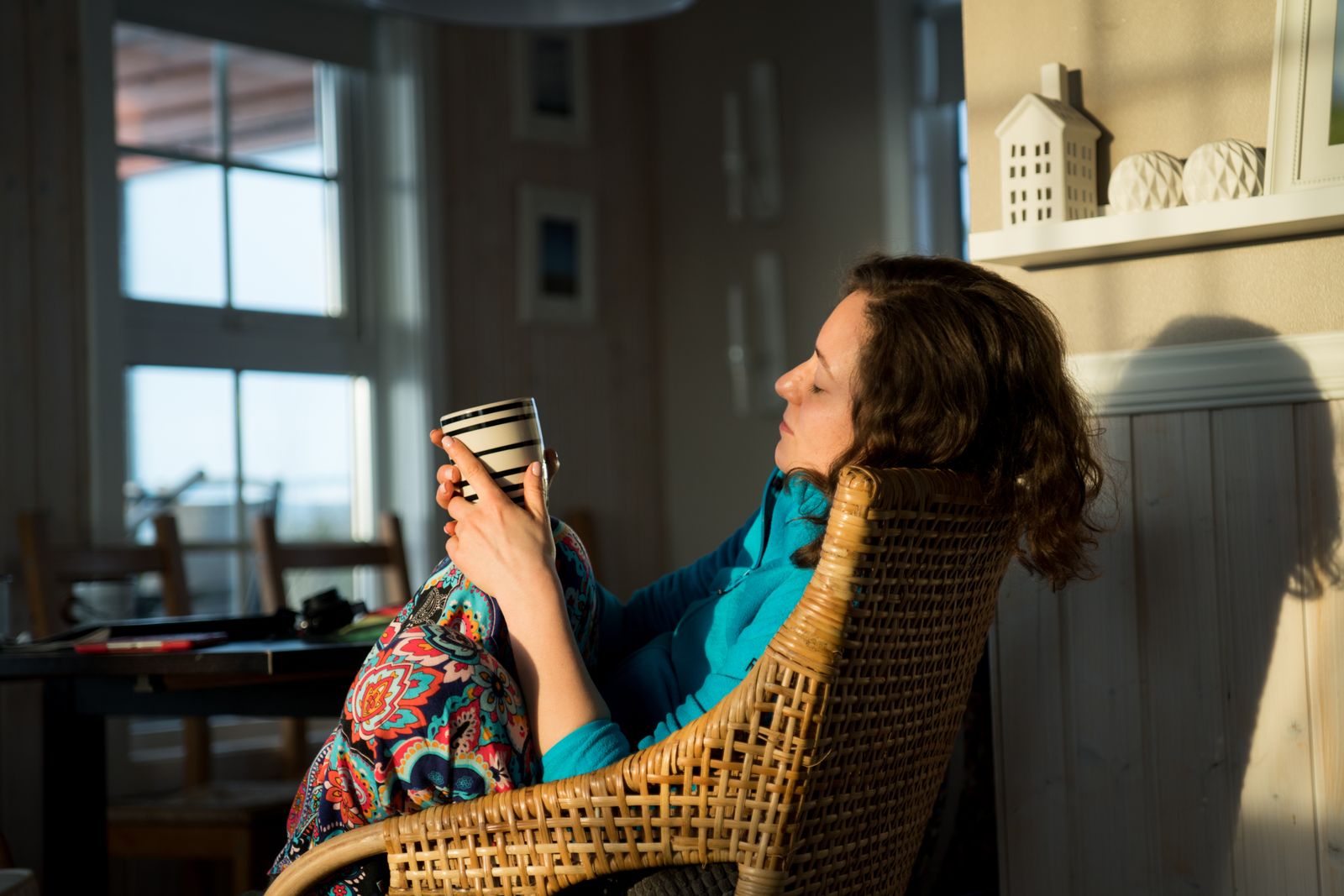 A woman sitting quietly in morning light with a cup of coffee